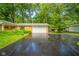 Charming single-story home with a brick facade, large garage door, and an expansive driveway surrounded by lush greenery at 10104 Sycamore Ln, Indianapolis, IN 46239