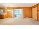 Open living area with wood-paneled walls, sliding glass doors, carpet flooring, and vintage chandelier at 10104 Sycamore Ln, Indianapolis, IN 46239