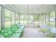 Bright sunroom featuring large windows and a charming seating area with a green, floral sofa and matching furniture set at 10104 Sycamore Ln, Indianapolis, IN 46239