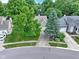 Aerial view of a home with mature trees, a well-maintained lawn, and a driveway leading to an attached garage at 1114 Clairborne Ct, Indianapolis, IN 46280