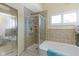 Bright bathroom featuring a glass shower and a soaking tub, with neutral tile surround and plantation shutters at 1114 Clairborne Ct, Indianapolis, IN 46280