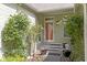 Inviting front porch with a bright red door, surrounded by lush plants and beautiful flower arrangements at 1114 Clairborne Ct, Indianapolis, IN 46280