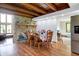 Open dining room features stone fireplace, hardwood floors, beamed ceilings, and stainless steel appliances at 13151 W Youth Camp Rd, Columbus, IN 47201