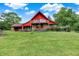 Wide view of the home's exterior, featuring a unique roof line, stone accents, dual decks, and lush lawn at 13151 W Youth Camp Rd, Columbus, IN 47201