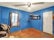Bedroom features blue walls, wood floors, and a window with patterned curtains at 2029 N Colorado Ave, Indianapolis, IN 46218