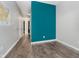 Open hallway featuring hardwood floors, neutral walls, and a pop of color with a bold blue accent wall at 20846 Winding Lake E Dr, Noblesville, IN 46062