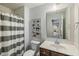 Bathroom with tiled shower and gray striped curtain, vanity, and dinosaur themed artwork at 2566 Maple Creek Dr, Westfield, IN 46074