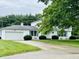Charming two-story home with white exterior, blue shutters, attached garage, and mature trees at 32 W Northeast Ct, Shelbyville, IN 46176