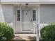 Close-up of white front door, showcasing charming details and inviting entryway framed by manicured shrubs at 32 W Northeast Ct, Shelbyville, IN 46176
