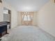 Bright, vacant living room with neutral carpet, chandelier, and large window with light drapes at 32 W Northeast Ct, Shelbyville, IN 46176