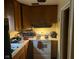 View of a compact kitchen with dated appliances and wooden cabinets at 8256 Meadowlark Dr, Indianapolis, IN 46226