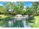 Picturesque pond view with fountains surrounded by mature trees on a sunny day at 9578 Cadbury Cir, Indianapolis, IN 46260