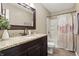 Charming bathroom featuring a granite countertop, dark wood vanity, and shower with floral curtains at 1011 Stevedon Ct, Plainfield, IN 46168