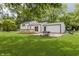 A white house with a lush backyard and a grill, partially shaded by a mature tree at 1537 Mutz Dr, Indianapolis, IN 46229