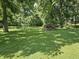 The house's large, grassy backyard is shaded by trees and features some uncollected yard waste at 2024 E 41St St, Anderson, IN 46013