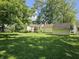 View of house's backyard and outbuilding, which features a lush green lawn and tree coverage at 2024 E 41St St, Anderson, IN 46013