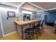 Basement bar area with wooden countertop, three barstools, mirrored backsplash, and decorative lighting at 37 E Waterbury Rd, Indianapolis, IN 46227