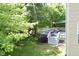 A backyard view of a wooden deck with patio seating, a grill, and an awning surrounded by a grassy lawn and trees at 3903 Junco Cir, Indianapolis, IN 46228
