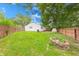 Fenced backyard with established lawn, mature trees and a stone fire pit at 5512 Lunsford Dr, Indianapolis, IN 46237