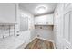 Bright laundry room featuring built-in cabinets, convenient access door, and modern wood-look flooring at 5512 Lunsford Dr, Indianapolis, IN 46237