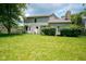 Expansive backyard featuring lush green lawn, mature trees, privacy bushes, and the home's rear exterior at 5640 Dapple Ct, Indianapolis, IN 46228