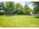 Fenced backyard with a lush green lawn, mature trees, and recreational equipment for outdoor enjoyment at 5640 Dapple Ct, Indianapolis, IN 46228