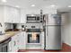 Well-lit kitchen featuring stainless steel appliances, white cabinetry, and wood flooring at 6300 Grouse Dr, Nineveh, IN 46164