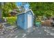 Charming blue shed with a white door, complemented by a quaint bench, nestled by a wooden dock and lush greenery at 6300 Grouse Dr, Nineveh, IN 46164