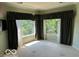 Bedroom with bay windows offering view of mature trees and a wall mounted TV at 8577 One W Dr # 301, Indianapolis, IN 46260