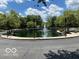 Community pond with a central fountain, surrounded by lush trees and scenic landscaping, offering a relaxing view at 8577 One W Dr # 301, Indianapolis, IN 46260
