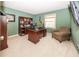 A home office featuring a wooden desk, shelving, comfortable chair, guitar, and a neutral-colored carpet for a professional workspace at 12602 Lockerbie Cir, Carmel, IN 46033