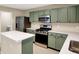 A modern kitchen featuring stainless steel appliances, with stylish sage colored cabinets for a contemporary touch at 14373 Orange Blossom Trl, Fishers, IN 46038