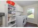Well-lit laundry room equipped with washer, dryer, storage cabinets, and a view of the outdoors at 3624 Newberry Rd, Plainfield, IN 46168