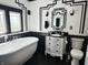 Art deco-style bathroom with freestanding tub, stylish vanity, and black and white accents at 4106 N Sherman Dr, Indianapolis, IN 46226