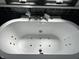 Close-up of soaking tub with jacuzzi jets in modern, tiled bathroom at 4106 N Sherman Dr, Indianapolis, IN 46226