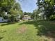 View of the side yard and the back of the home with lots of green grass, mature trees, and several vehicles at 4106 N Sherman Dr, Indianapolis, IN 46226