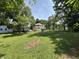 View of the side yard and the back of the home with lots of green grass, mature trees, and several vehicles at 4106 N Sherman Dr, Indianapolis, IN 46226