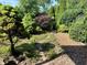 Landscaped backyard featuring a stone path and gravel, surrounded by lush plants and trees at 474 N Kristi Rd, Martinsville, IN 46151