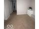 Neutral bedroom with a dresser, carpeted floor, and view into the hallway at 6548 Frankenberger Dr, Indianapolis, IN 46237