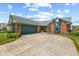 Charming house with a brick and vinyl exterior, an attached garage, and a paved driveway, all nestled in a green lawn at 7384 Southern Lakes Dr, Indianapolis, IN 46237