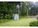 The backyard shows a well-maintained lawn and a small storage shed set among mature trees at 7780 Cree Trl, Indianapolis, IN 46250