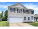 A two-story home featuring tan siding, a white garage door, and red window shutters at 10658 Pavilion Dr, Indianapolis, IN 46259
