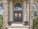 Elegant entryway featuring double wooden doors with decorative glass, framed by stone pillars and lush greenery at 3270 Cherokee Cir, Bargersville, IN 46106