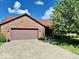 Charming brick house showcasing a two-car garage, mature trees, and a well-maintained lawn at 3400 W Riggin Rd, Muncie, IN 47304