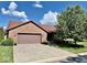 Charming brick home featuring an attached two-car garage and landscaped front yard at 3400 W Riggin Rd, Muncie, IN 47304