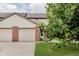 A townhome with two-car garage and beige siding sits on a manicured lawn at 5370 Bay Harbor Dr, Indianapolis, IN 46254
