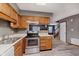 Open-concept kitchen with wooden cabinets, appliances, laminate floors, and a view to the living room at 5370 Bay Harbor Dr, Indianapolis, IN 46254