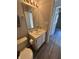 A compact bathroom featuring a single sink vanity, neutral walls, and wood-look flooring at 7313 Shanna Cir, Indianapolis, IN 46236