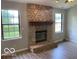 Living area featuring a stone fireplace, hardwood floors, and two large windows at 7313 Shanna Cir, Indianapolis, IN 46236