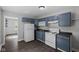 Efficient kitchen with blue cabinets, white appliances, and dark countertops at 7424 North Dr, Lawrence, IN 46226